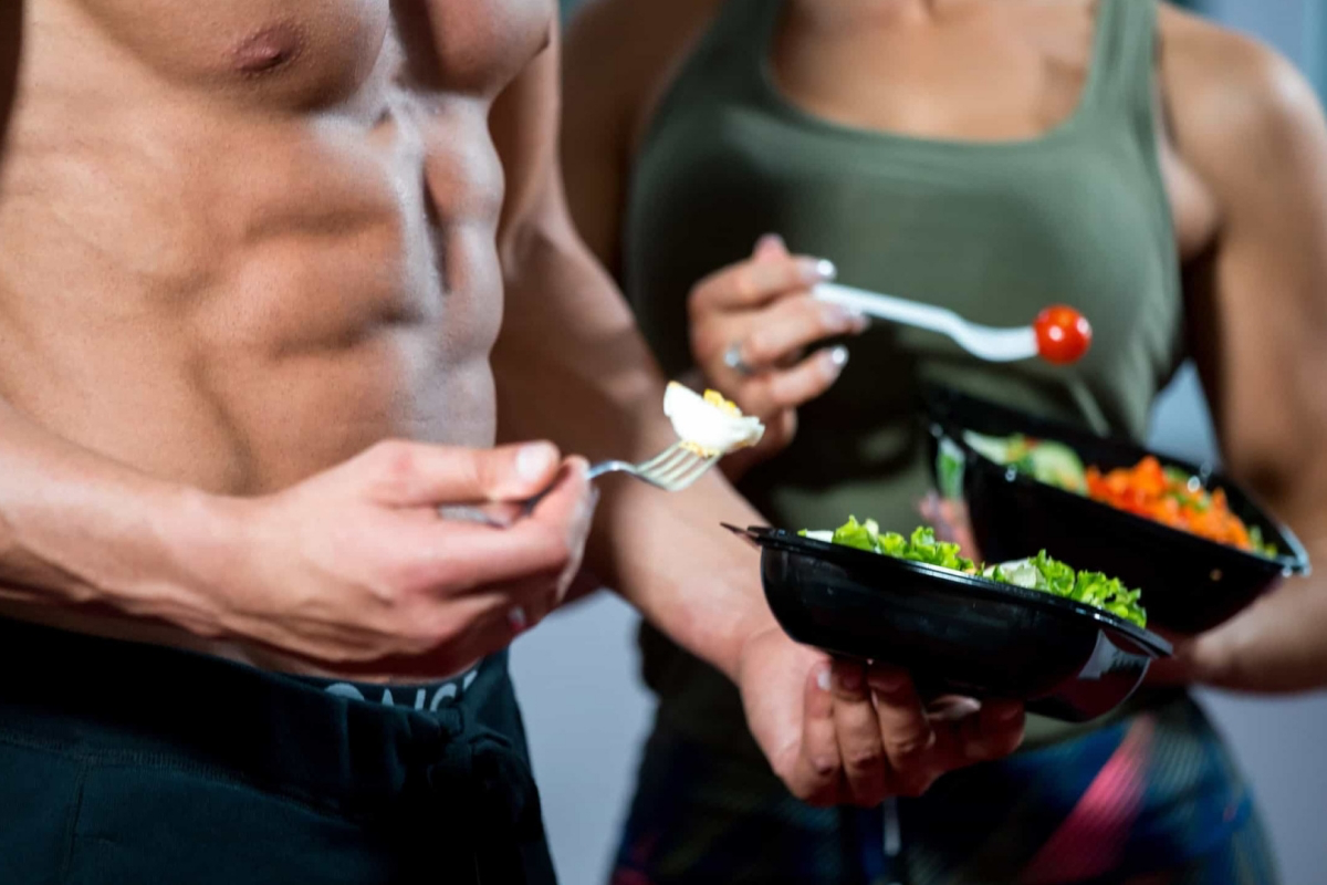 Спортсмены с подтянутой фигурой держат контейнеры с салатом и творогом, демонстрируя основы правильного питания для активного образа жизни.