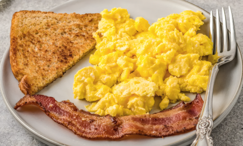 Омлет с ломтиком тоста и полоской бекона на тарелке